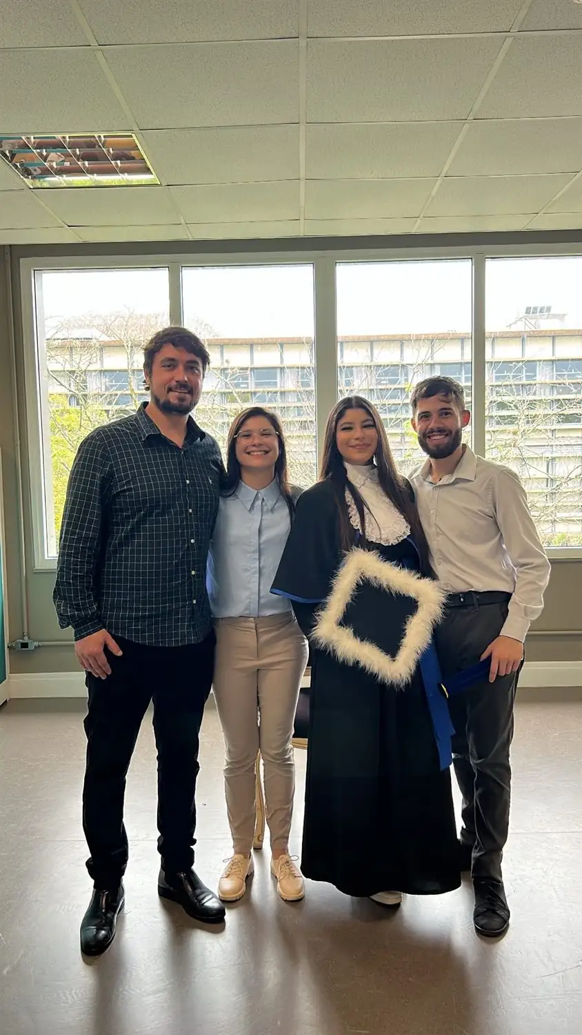 Moradora de beca de formatura ao lado de amigos da casa