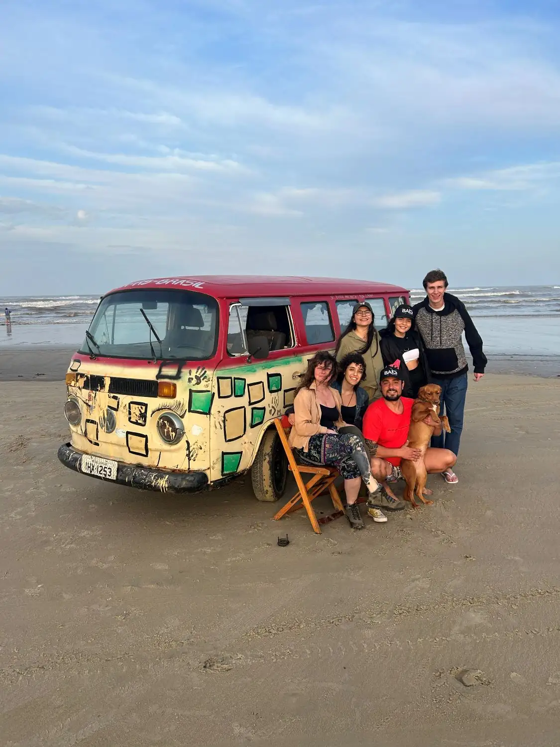 Moradores em volta de uma Kombi pintada na areia da praia