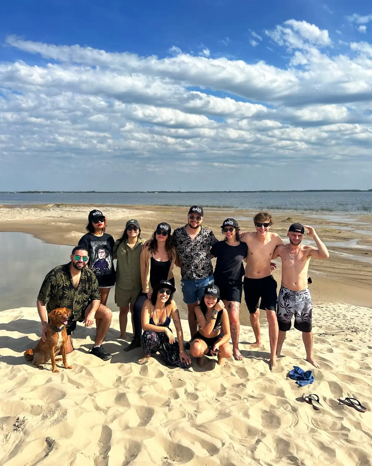 Moradores da Bah na praia, de boné da Bah, com um cachorro