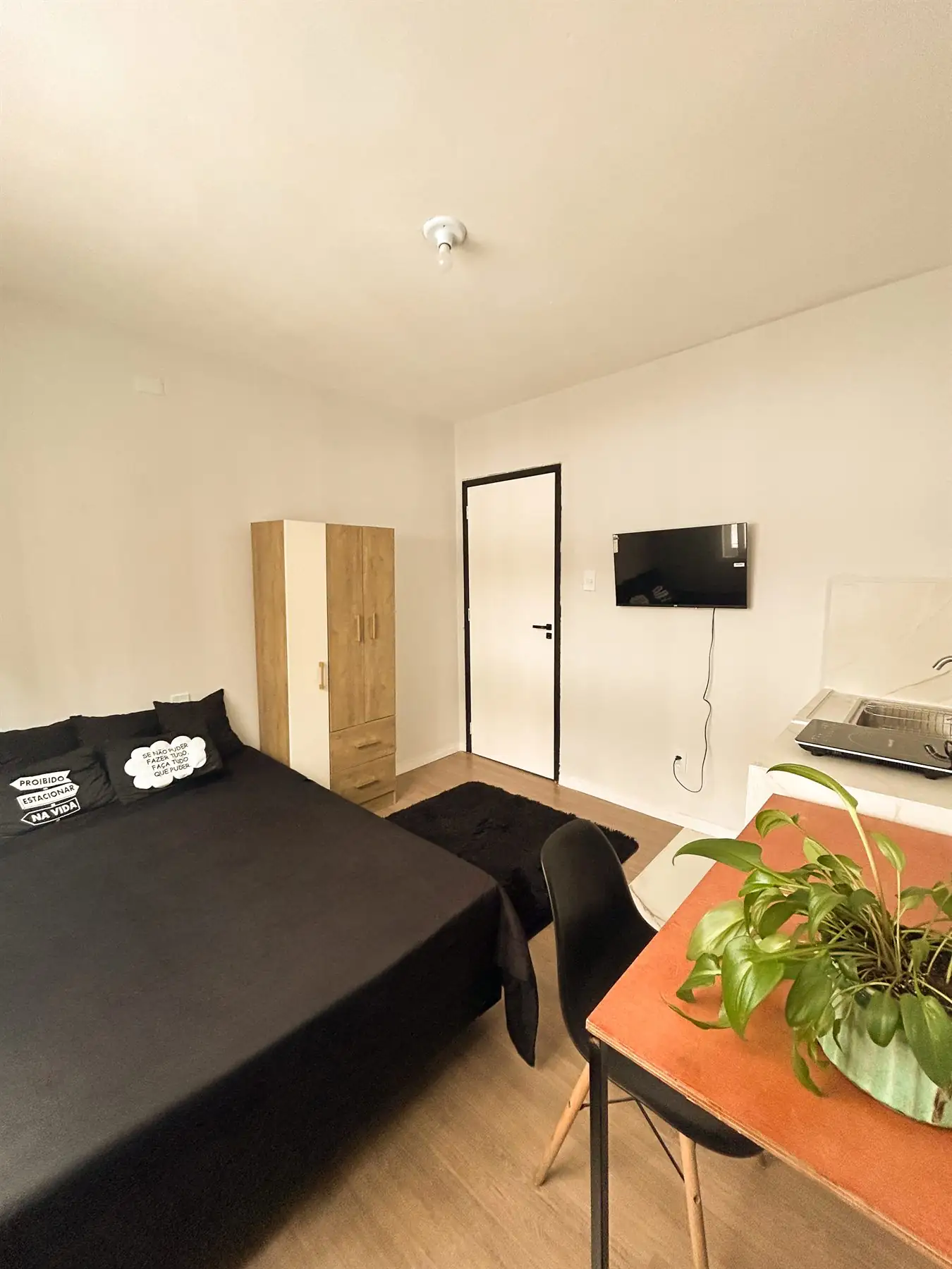 Estúdio do Bah Studios com cama de casal, armário, TV e cozinha própria